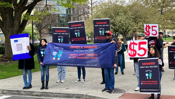 Gruppe Menschen hält Schilder mit Forderung an Danaher Preis zu senken