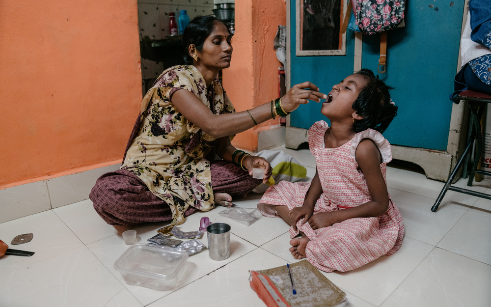 Mutter gibt ihrer Tochter Medikamente gegen Tuberkulose in Indien