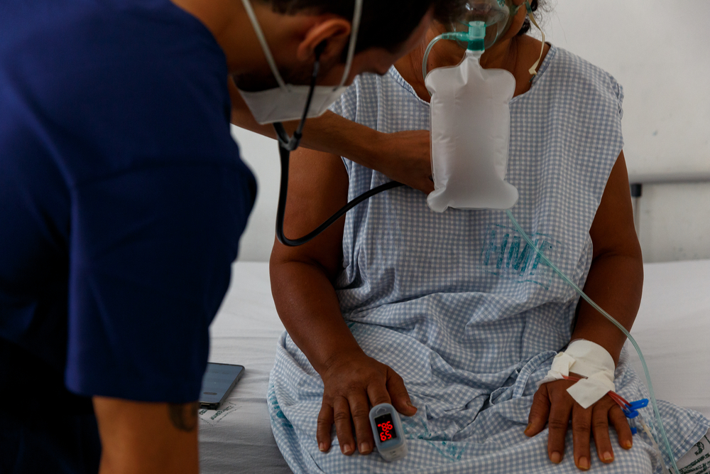 Eine Patientin, die eine Sauerstoffmaske trägt, wird untersucht