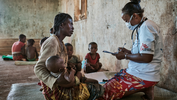 Eine Mitarbeiterin von Ärzte ohne Grenzen sitzt einer Patientin mit Kind gegenüber