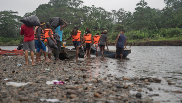 Menschen mit Rettungswesten steigen in ein Kanu auf einem Fluss ein