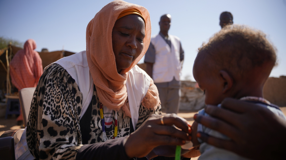 Sudan: Mitarbeiterin prüft auf Mangelernährung an Arm von Kleinkind
