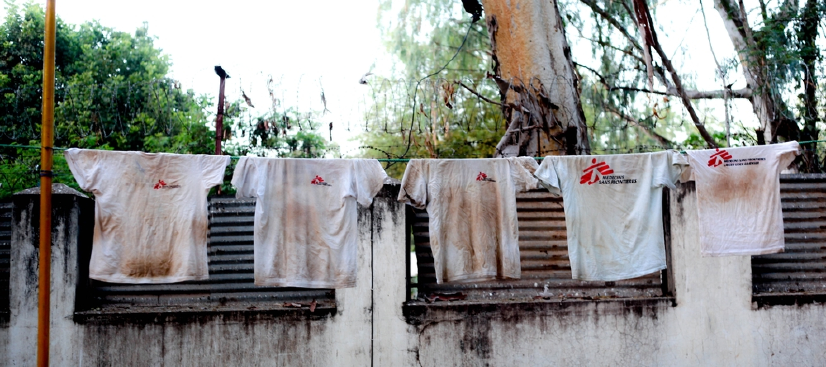 Schmutzige weiße T-Shirts mit Ärzte ohne Grenzen Audruck hängen auf einer Wäscheleine