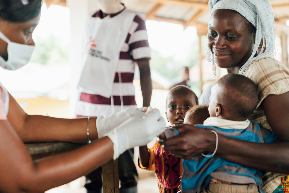 Foto einer Krankenpflegerin die ein Kind auf Malaria testet