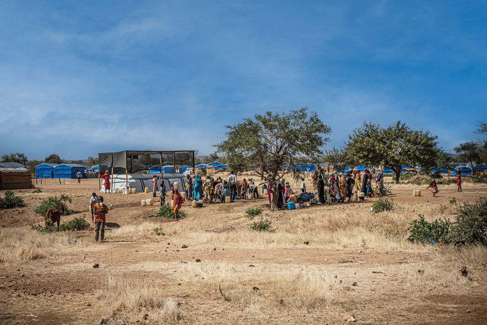 Menschen in Geflüchtetencamp stehen an Wasserverteilung an