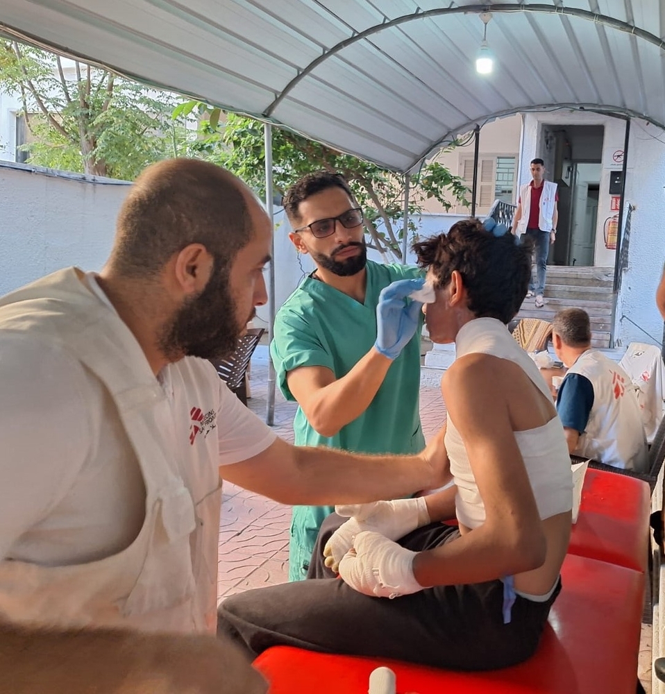 Zwei Pfleger versorgen einen Jungen mit Verbrennungen am Oberkörper.