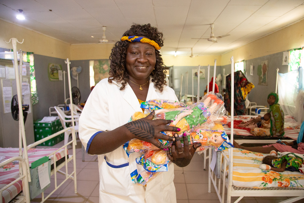 Frau steht in einem Raum mit Krankenhausbetten und hat Spielzeug in ihren Händen