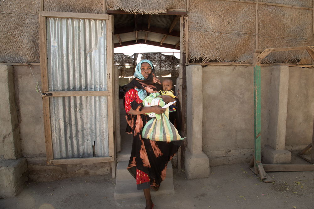 Mutter mit Kind auf dem Arm verlässt Gebäude
