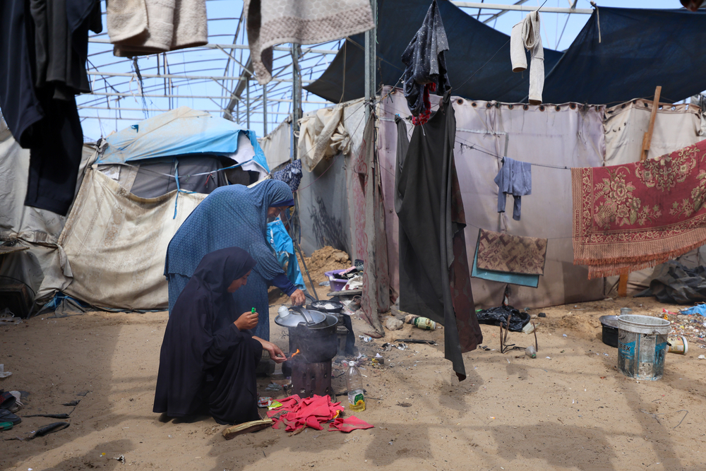 2 Frauen Kochen inmitten einer behelfsmäßigen Unterkunft.