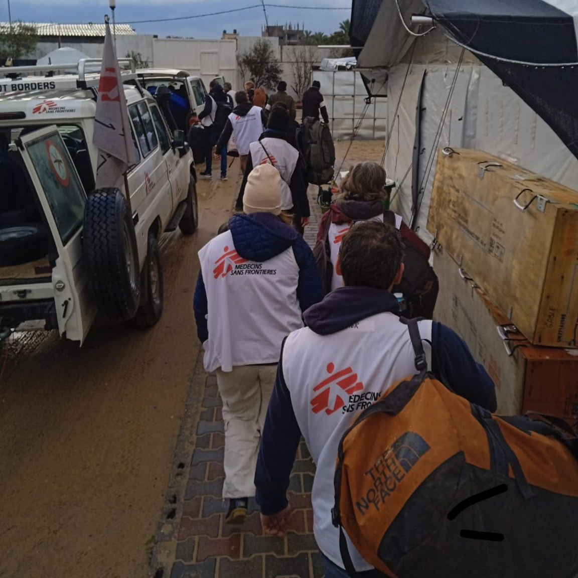 Mitarbeitende laufen mit Gepäck zu Fahrzeugen