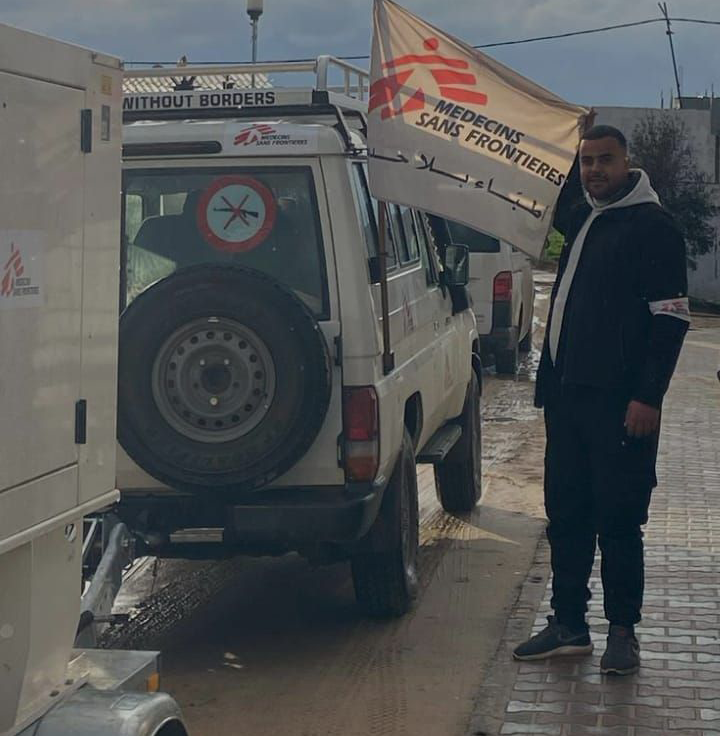 Mitarbeitender steht neben Fahrzeug mit Flagge von Ärzte ohne Grenzen