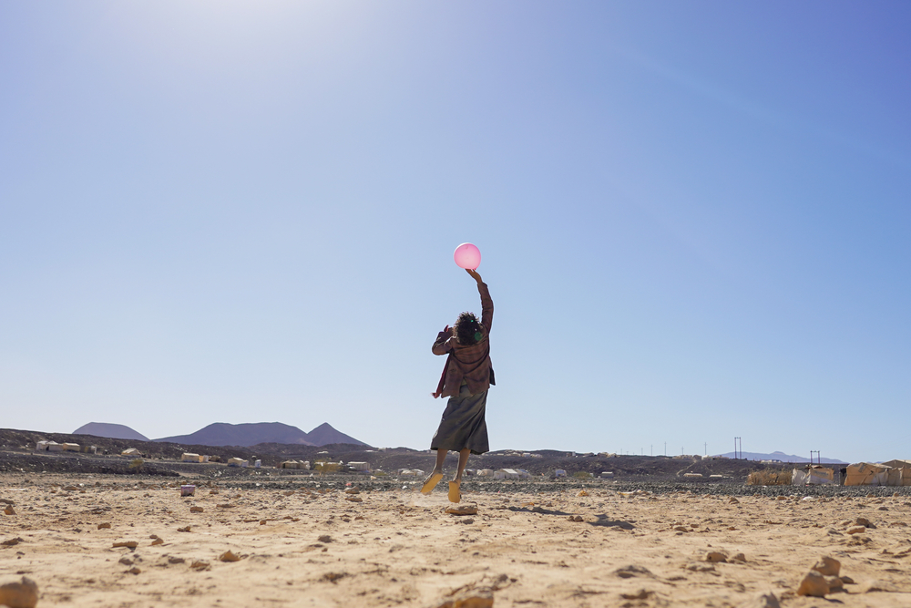 Ein Junge springt in der Wüste bei Marib hoch mit einem Luftballon in der Hand