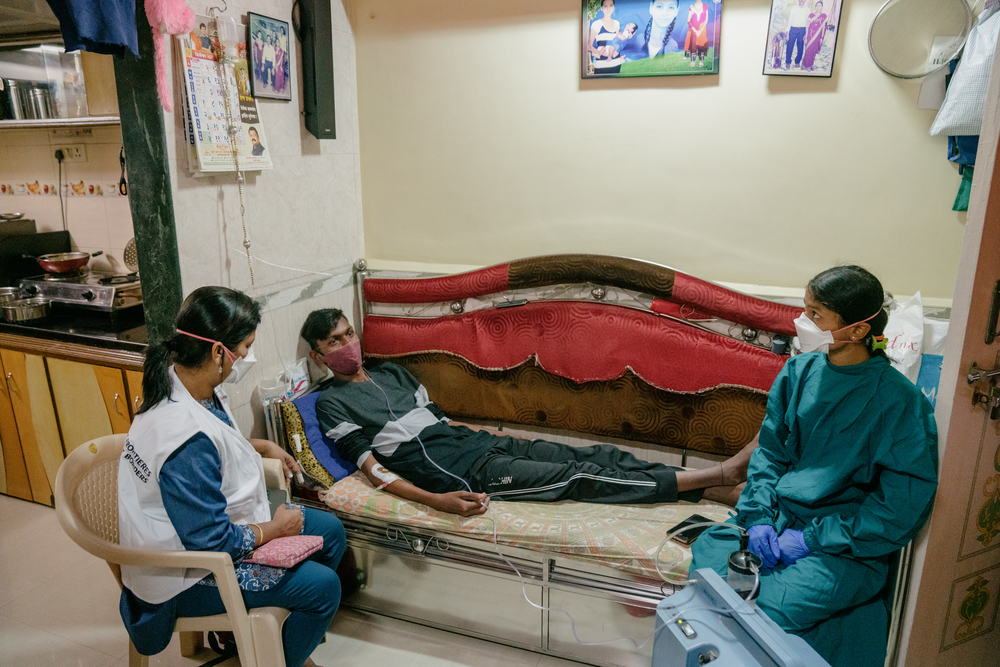 Ein Tuberkulose Patient mit zwei Mitarbeiterinnen von Ärzte ohne Grenzen bei der Behandlung