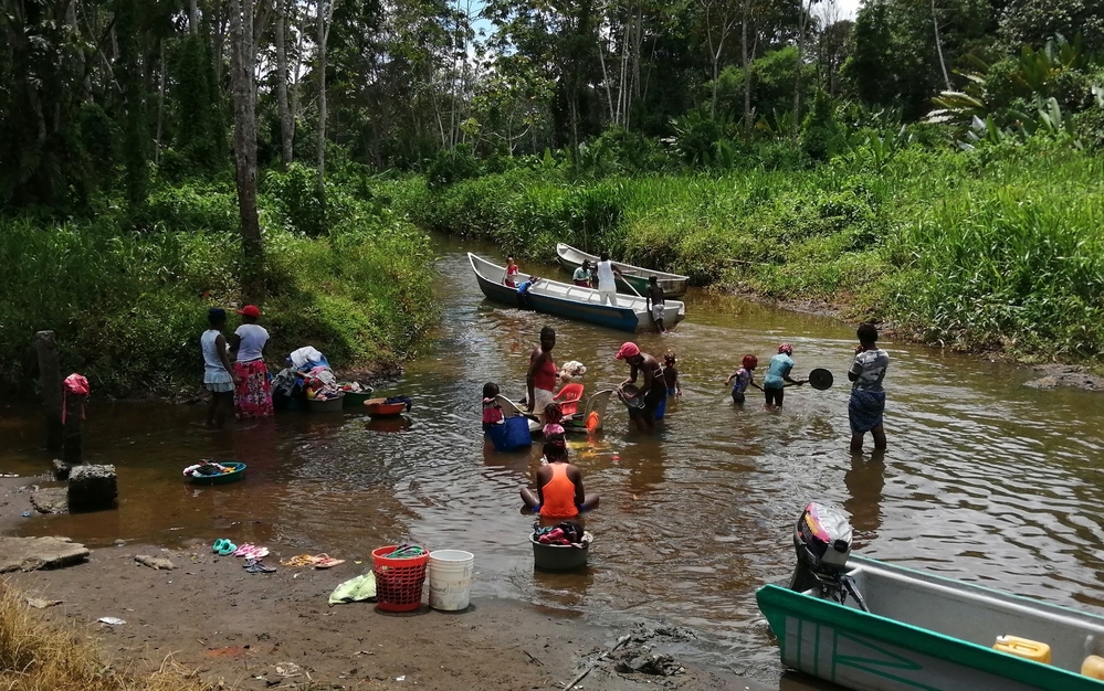 Ein friedlicher Moment: Erwachsene gehen ihren Aufgaben nach, während Kinder im Wasser spielen.