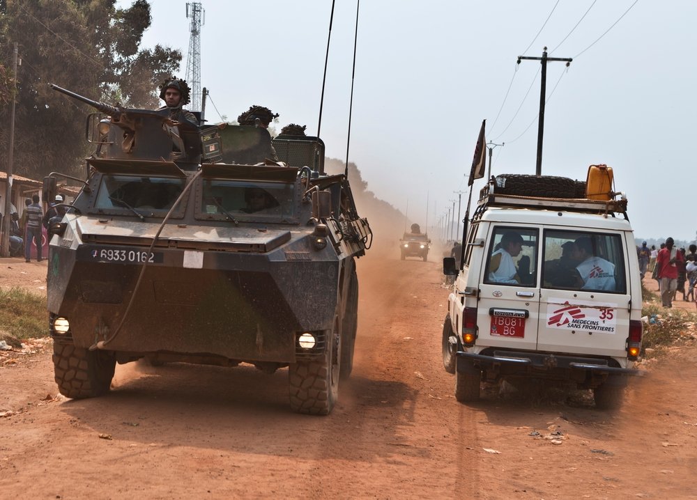 Ein Ärzte ohne Grenzen Auto fährt neben einem Militärfahrzeug 