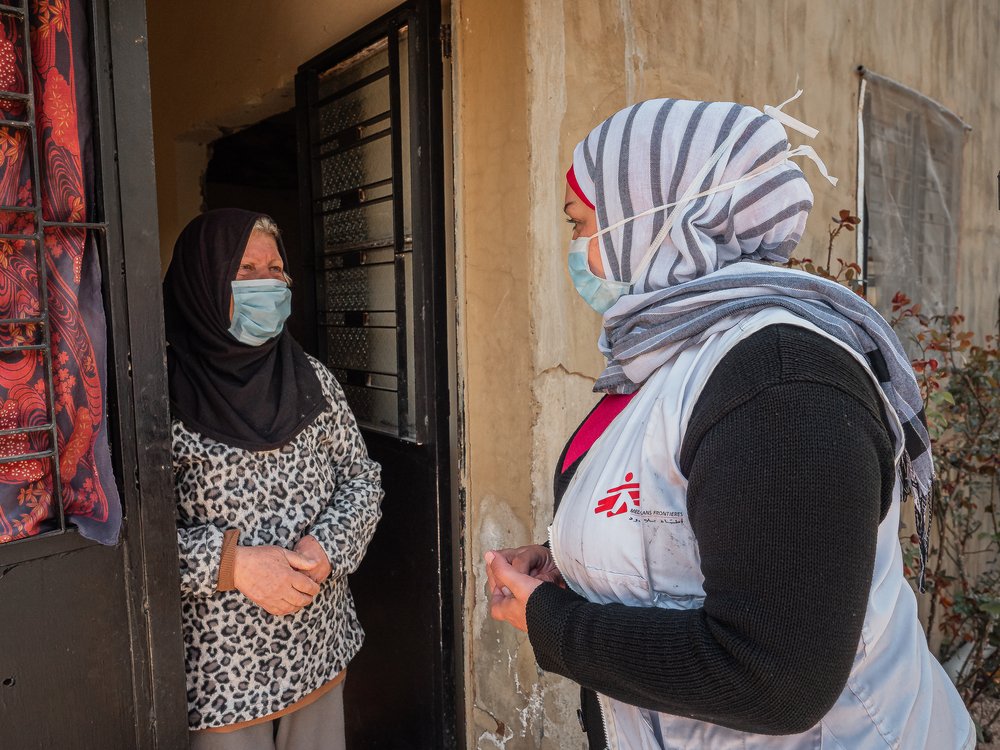 Zwei Frauen unterhalten sich an der Tür, eine trägt eine Ärzte ohne Grenzen Weste