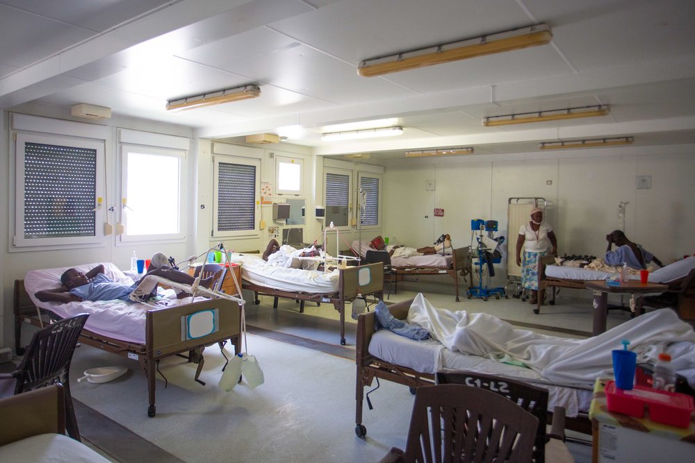 Patient*innen liegen in ihren Betten in einem Krankenhauszimmer.