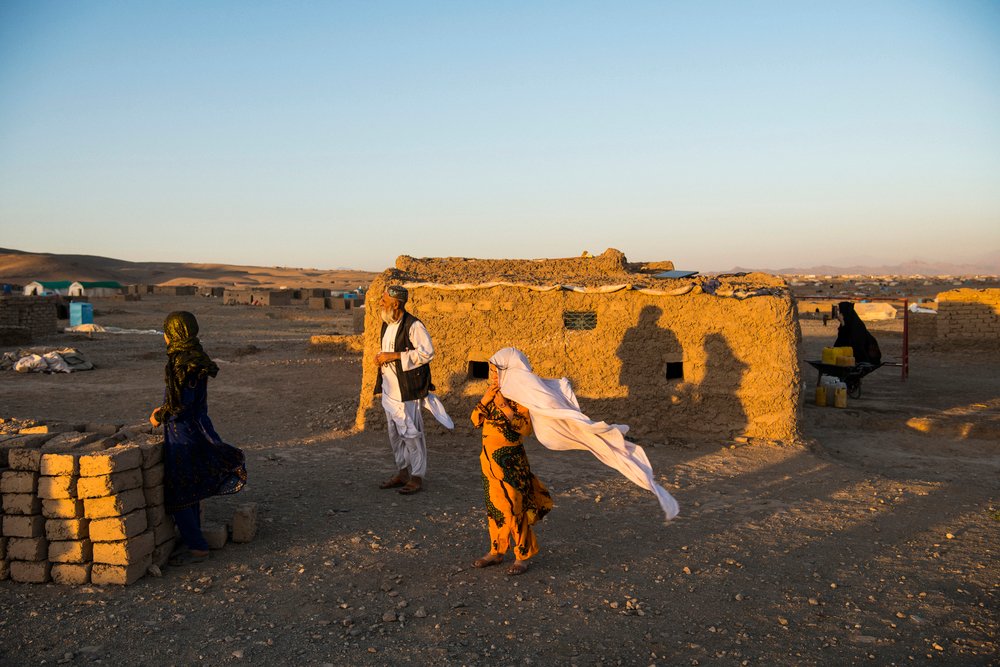 Zwei Frauen und ein Mann stehen vor einer kleinen Mauer in einem wüstenähnlichen Gebiet in der Abendsonne