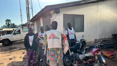 Fünf Männer in Ärzte ohne Grenzen Shirts neben Motorrädern