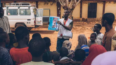 Ein Health Promoter verteilt Broschüren über die Krankheit Noma