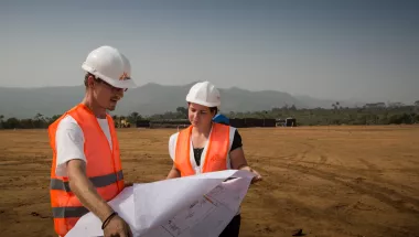Zwei Mitarbeiter*innen mit Berufsprofil Architekt*in, Bauingenieur*in  auf Gelände mit Bauplan