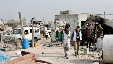 Gaza Blockade: Mitarbeitende laufen zwischen zerstörten Gebäuden