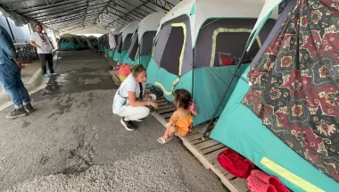 Kniende Mitarbeitende spricht mit Kind