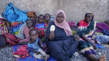 Frau zeigt amputierten Arm, daneben vier Kinder, eine Frau