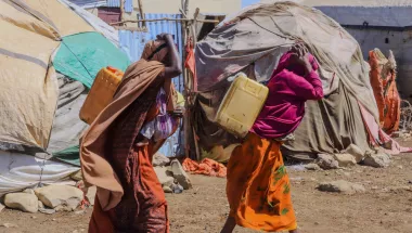 Zwei Frauen tragen Wasserkanister in Camp