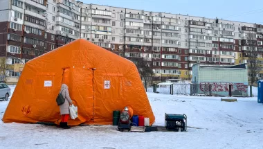 Zelt im Schnee - davor Person neben Generator