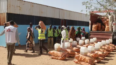 Mehrere Personen laden Säcke mit Nahrung ab und sortieren diese.