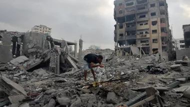 Ein Mensch an Wasserleitung zwischen den Trümmern zerstörter Gebäude