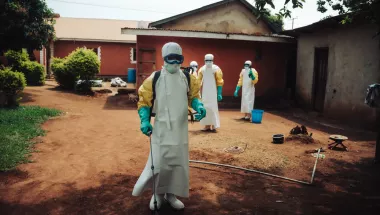 Vier unserer Mitarbeiter*innen stehen in vollständiger Schutzkleidung mit Sprühgeräten auf einem Hof zwischen mehreren Gebäuden.
