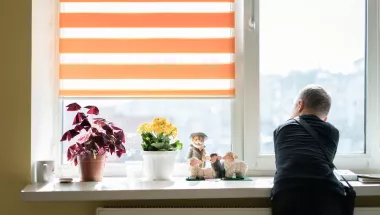 Ein Junge lehnt an einer Fensterbank und schaut aus dem Fenster
