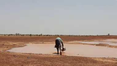 Person schöpft Regenwasser vom Boden