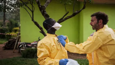 Hygienespezialist hilft Kollege in Schutzkleidung