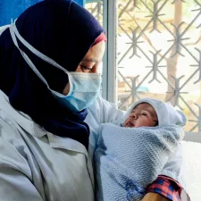 Unterstützen Sie unsere Arbeit durch die Schaltung einer Anzeige oder eines Werbebanners. Eine Hebamme hält ein Baby