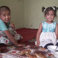 Tuberkulose Bibisoleha und Zainidin Ein Junge und ein Mädchen sitzen auf dem Boden ihres Wohnhauses.