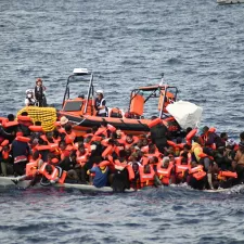 Ein Schlauchboot liegt neben einem massiv überfüllten Holzboot