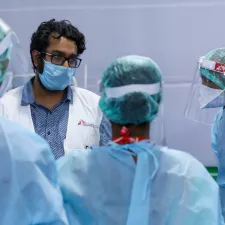 Vier Ärzte beraten sich. Sie sind komplett in Schutzkleidung gehüllt.