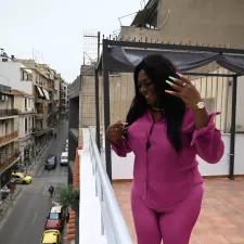 Patient*innen wie Yuli machen sich für ihre Mitmenschen stark. Eine Frau steht auf Balkon und lacht.