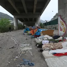Provisorische Unterkunft aus Betten und Zelten unter einer Brücke