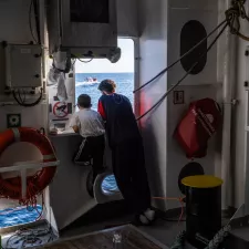 Zwei Jungen stehen am Fenster eines Schiffes und schauen auf das Meer.