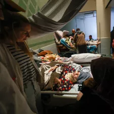 Behandelnde und Angehörige am Bett einer Patientin.