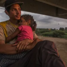 Foto eines jungen Mannes, der seine Tochter im Arm hält Flucht: junger Mann mit Tochter auf Arm