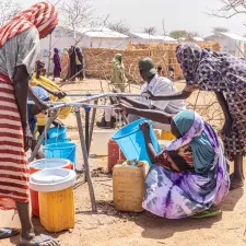 Frauen füllen Wasserkanister im Vertriebenencamp Alacha, Tschad Frauen füllen Wasserkanister im Vertriebenencamp Alacha, Tschad