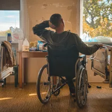 Patient sitzt im Rollstuhl in einem Krankenhauszimmer