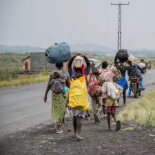 D. R. Kongo: Menschen laufen an Straßenrand mit Gepäck beladen