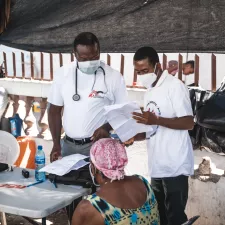 Zwei Ärzte sprechen mit einem Patienten in einem Camp für Vertriebene