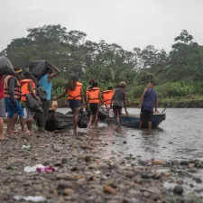 Menschen mit Rettungswesten steigen in ein Kanu auf einem Fluss ein